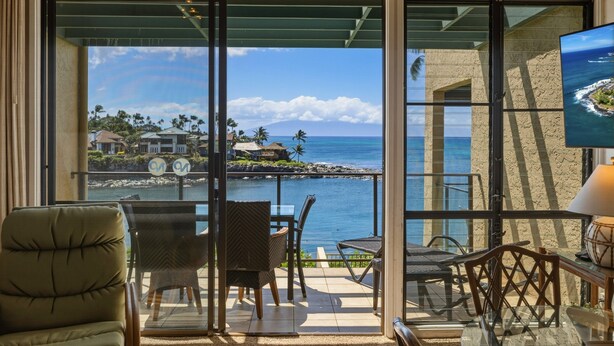 A balcony with a view of the ocean, a chair, a table, and a lamp. - Oceanfront 2br Loft With Sunset Views - Unit C23 1 Bedroom Condo (Lahaina)