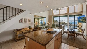 A spacious kitchen with a granite countertop, wooden cabinets, and a large island. - Oceanfront 2br Loft With Sunset Views - Unit C23 1 Bedroom Condo (Lahaina)