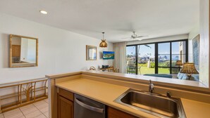 Eine moderne Küche mit einem großen Fenster, einem Deckenventilator und Blick ins Freie.