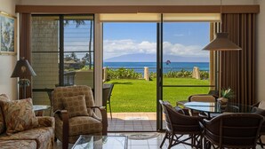 A room with a balcony, a dining area, and a view of the ocean. - Oceanfront Maui Retreat At Napili Point - Unit B16 1 Bedroom Condo (Lahaina)