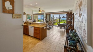 A spacious kitchen with a large island, a dining area with chairs, and a view of the ocean. - Oceanfront Maui Retreat At Napili Point - Unit B16 1 Bedroom Condo (Lahaina)