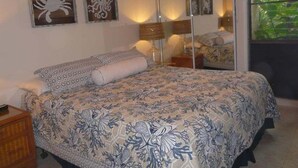 Ein Schlafzimmer mit Bett, Nachttisch, Schminktisch und einem großen Spiegel.