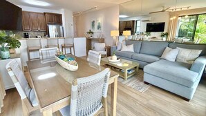 A modern living room with a dining area, a sofa, and a TV. - Oceanfront Family Friendly 2br Maui - Unit B29 1 Bedroom Condo (Lahaina)