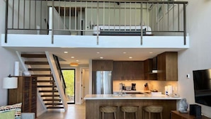 A spacious loft with a kitchen, dining area, and a staircase leading to an upper level. - Napili Point Point Oceanfront 2br Loft - Unit C2 1 Bedroom Condo (Lahaina)