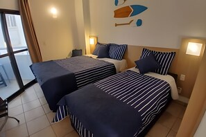 A hotel room with two beds, striped bedding, a desk, and a chair. - Clube XV (Santos)