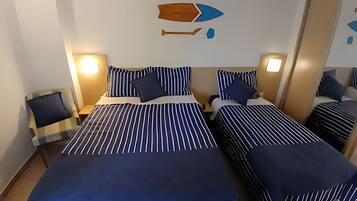 Quarto de hotel com duas camas, roupa de cama listrada e um adorno de parede com um barco.