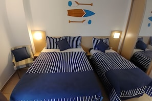 A hotel room with two beds, striped bedding, and a wall decoration of a boat. - Clube XV (Santos)