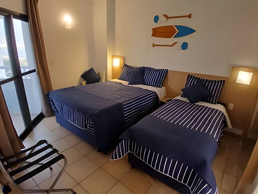 Habitación de hotel con dos camas, una silla y vistas al exterior.
