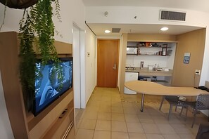 A modern kitchen with a built-in oven, a sink, and a countertop. There is a wooden door leading to another room. - Clube XV (Santos)