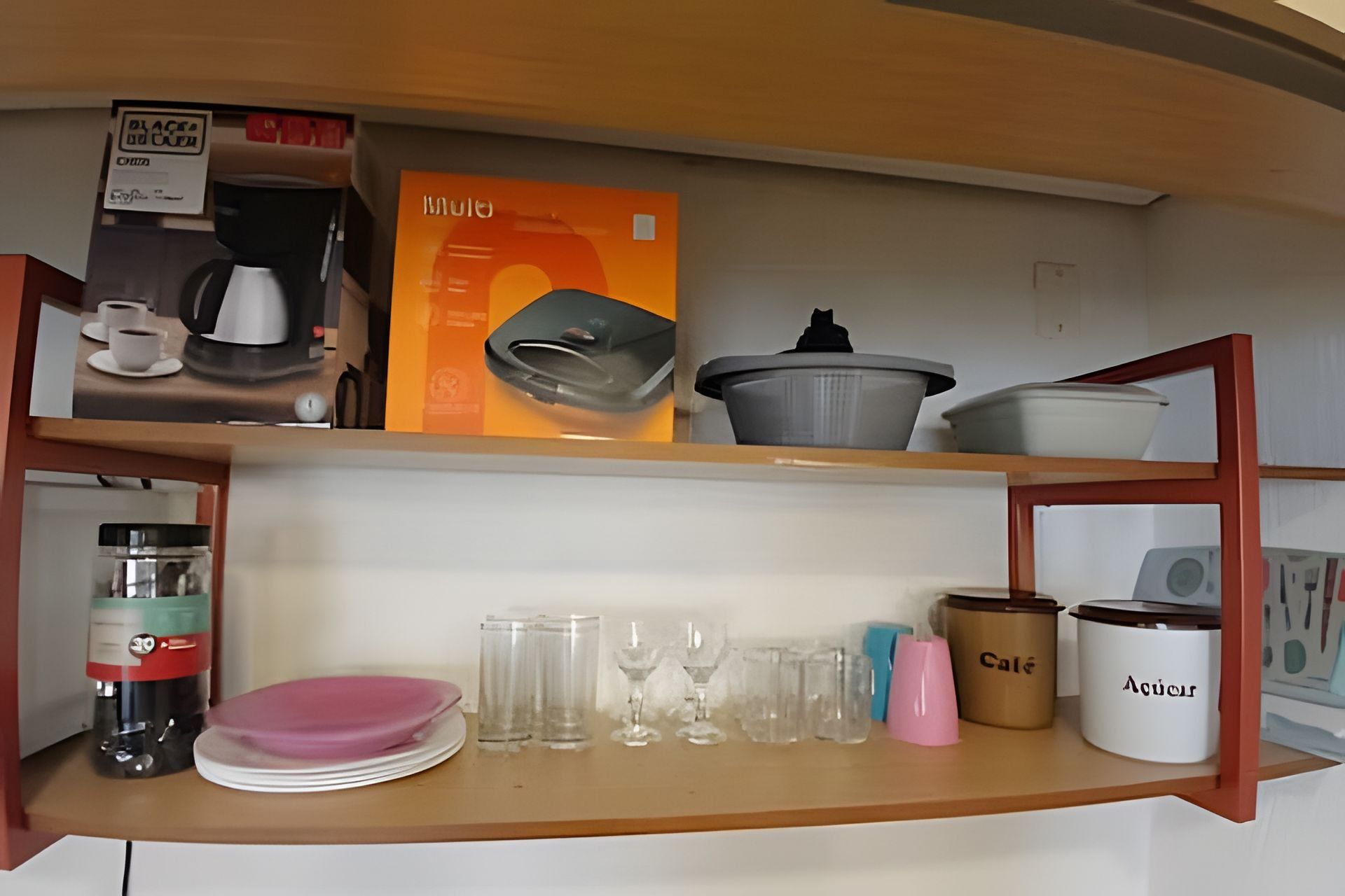 A kitchen shelf with a coffee maker, a box labeled 'mule', and various kitchenware including plates, glasses, and containers.