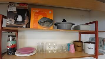 A kitchen shelf with a coffee maker, a box labeled 'mule', and various kitchenware including plates, glasses, and containers.