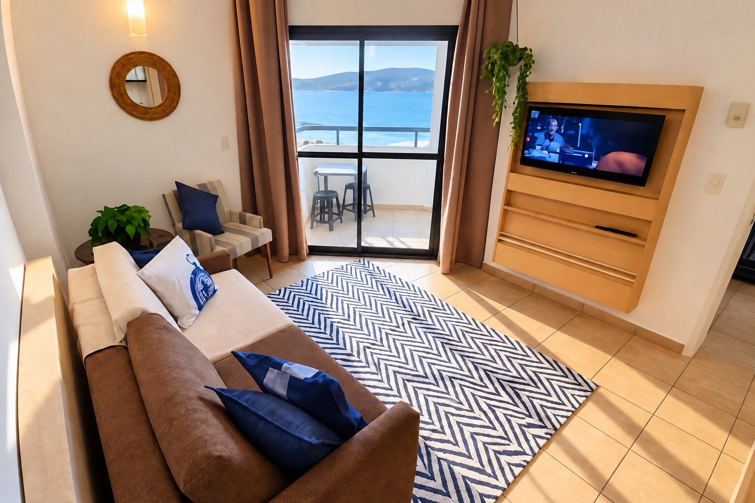 A living room with a sofa, TV, and a view of the sea.