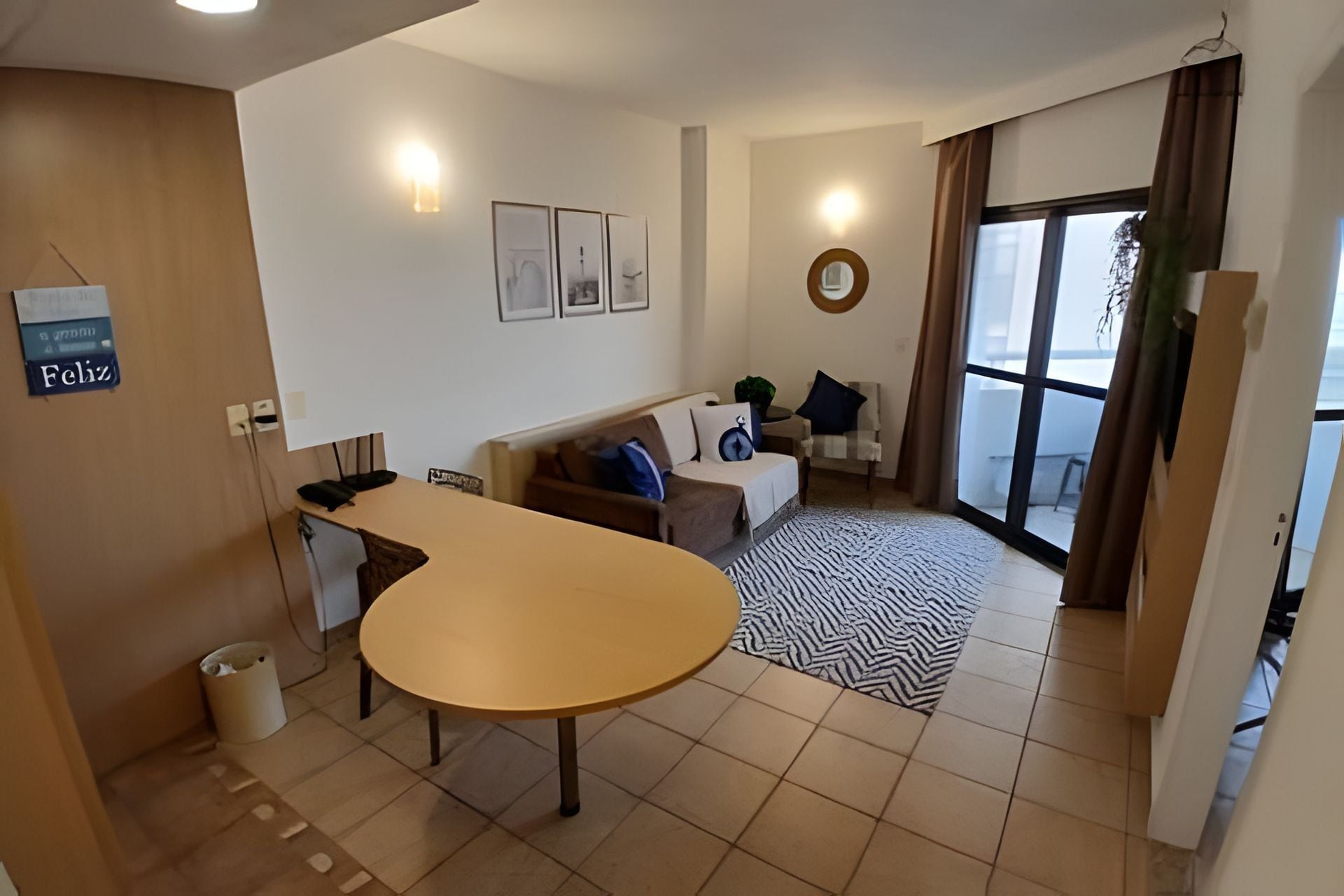 Uma sala de estar moderna com uma mesa redonda, um sofá e uma janela grande.
