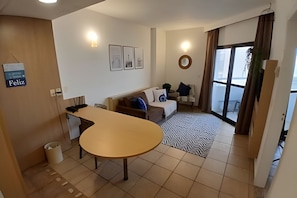 A modern living room with a round table, a sofa, and a large window. - Clube XV (Santos)