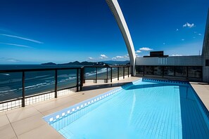 A modern rooftop pool with a clear view of the ocean and distant mountains. - Clube XV (Santos)