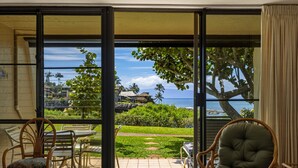 A room with a sliding glass door leading to a patio with a table, chairs, and a grill. - Oceanfront Condo Near Napili Bay 1br - Unit A17 1 Bedroom Condo (Lahaina)