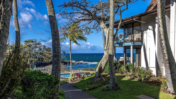 A pathway leading to a pool with a view of the ocean and a building with large windows. - Oceanfront Condo Near Napili Bay 1br - Unit A17 1 Bedroom Condo (Lahaina)
