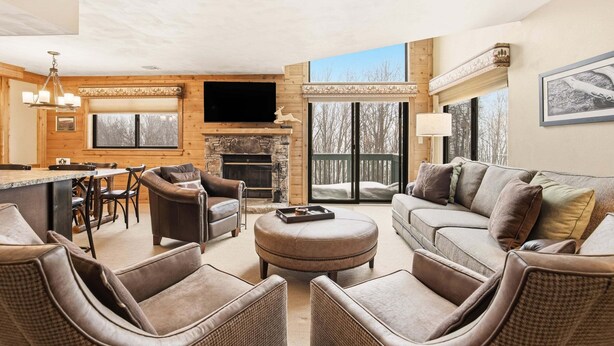 A cozy living room with a fireplace, comfortable seating, a dining area, and a large window. - Seven Springs Meadowridge 3brloft Premier-cssv8011 3 Bedroom Condo (Champion)