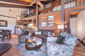 A spacious living area with a high ceiling, a kitchen in the background, and a staircase leading to an upper level. - Tahoe City - Lake Forest Condo 3 Bedroom Condo (Tahoe City)