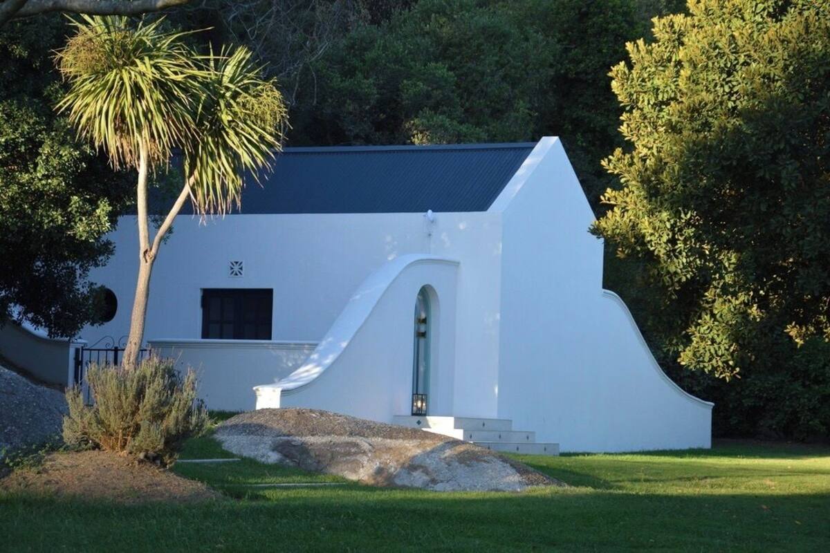 A white building with a curved roof, a small arched entrance, and a window.