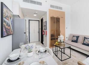 Uma sala de estar moderna com uma mesa de jantar posta para quatro pessoas, um sofá e um guarda-roupa com porta de vidro deslizante.