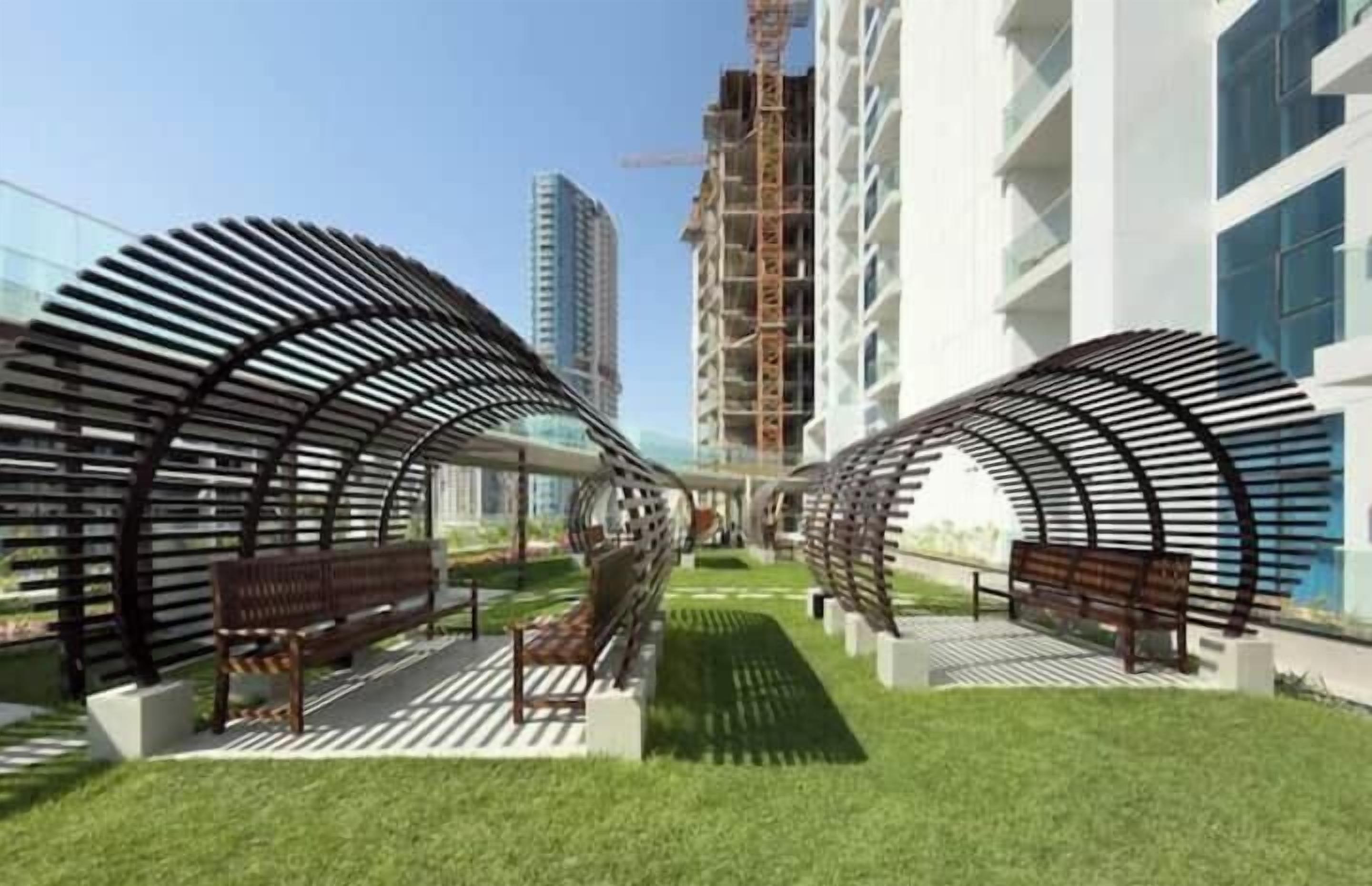 A modern building with a curved architectural design, featuring outdoor seating areas and a pathway.