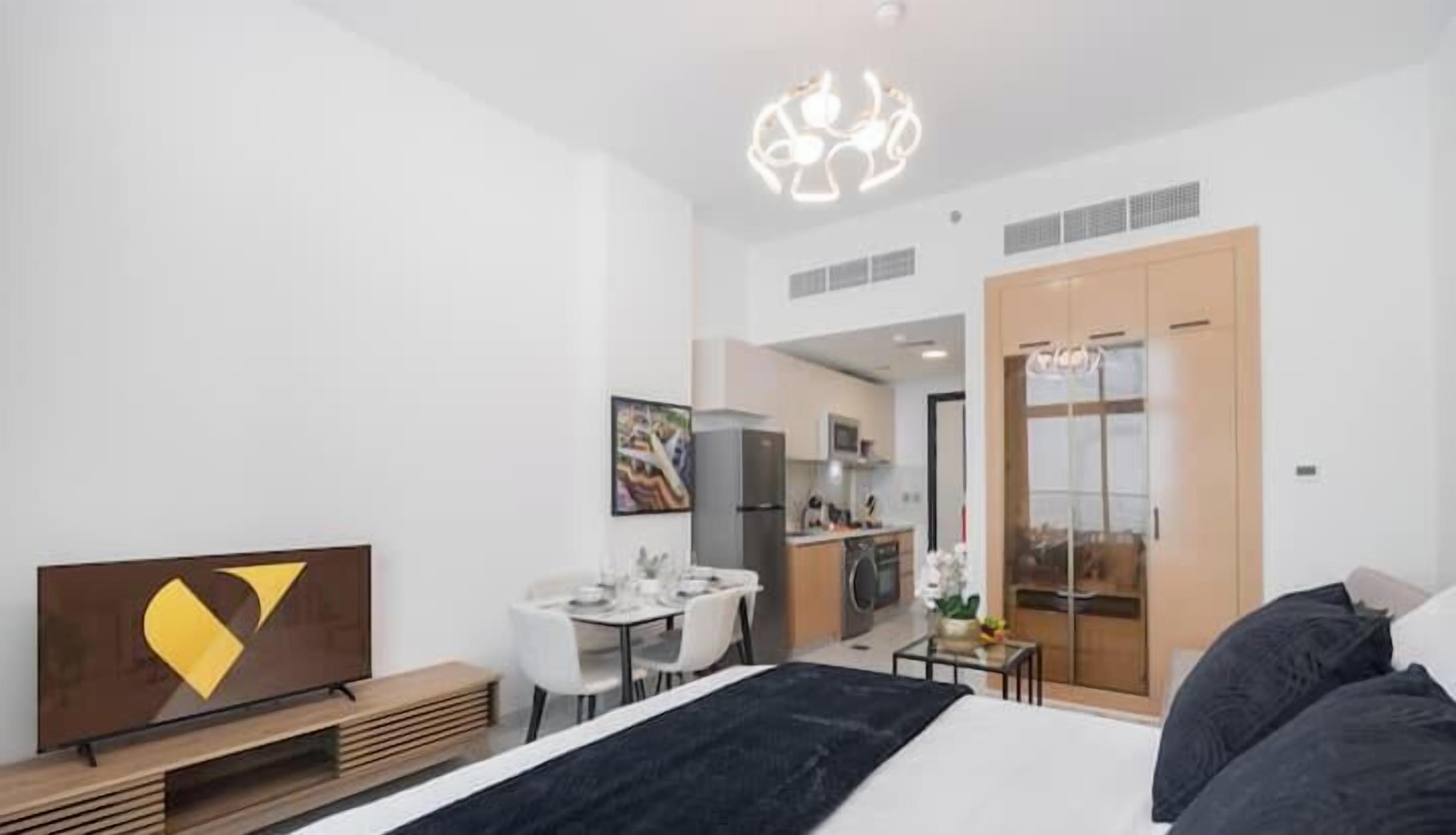 Una habitación de hotel moderna con cama, escritorio, silla, mesa de comedor y zona de cocina.