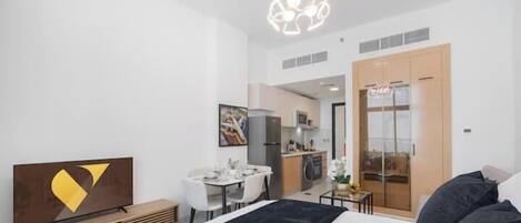Una habitación de hotel moderna con cama, escritorio, silla, mesa de comedor y zona de cocina.