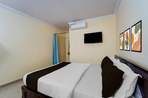 A hotel room with a bed, a flat-screen TV, and framed artwork on the wall.