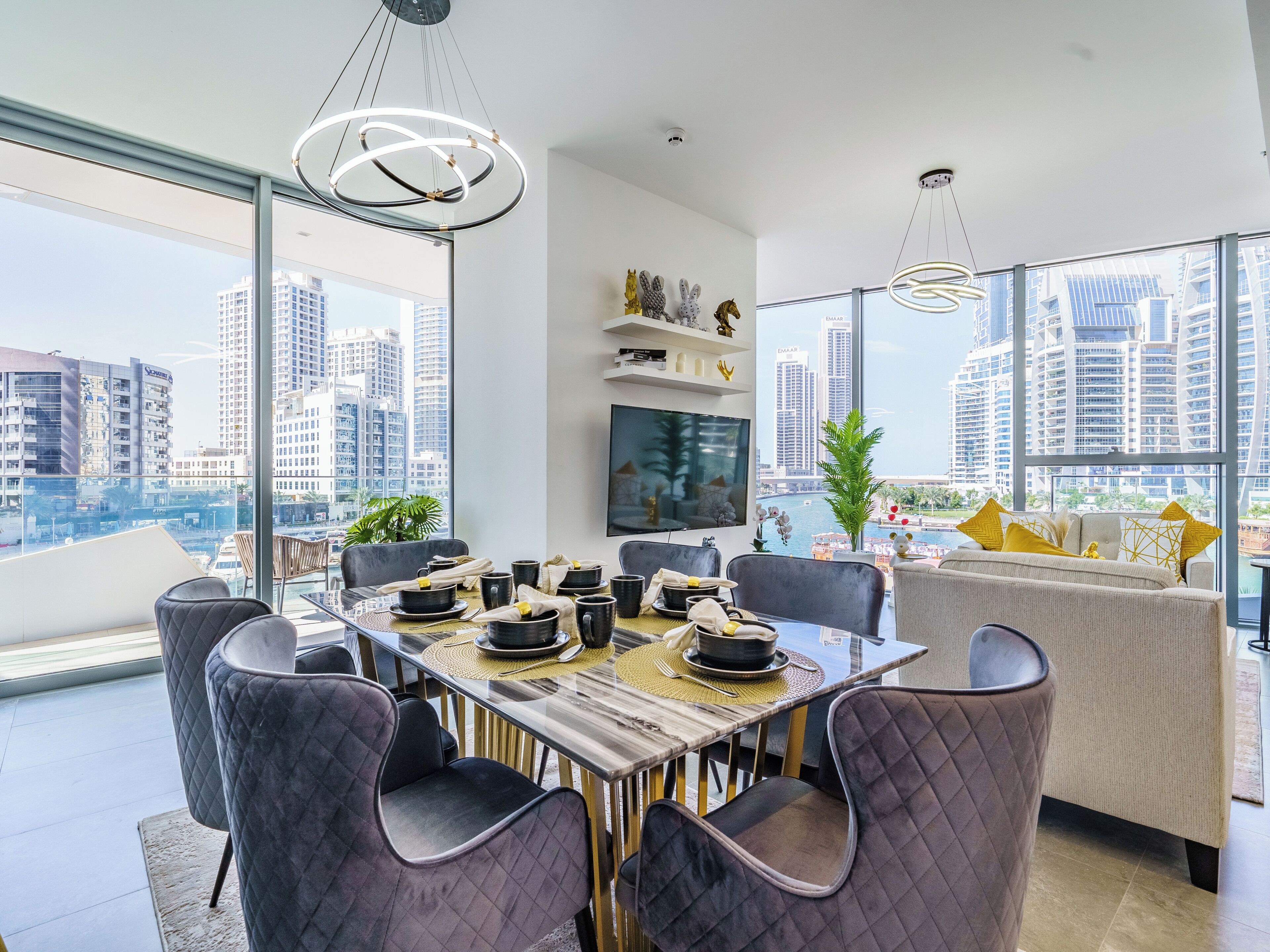 A modern dining area with a glass table, cushioned chairs, and a city view.