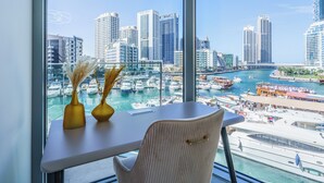 Habitación de hotel moderna con un amplio ventanal que da a un puerto deportivo y al horizonte urbano.