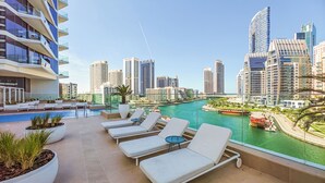 Un área de piscina en la azotea con sillones reclinables y vistas al horizonte de la ciudad.