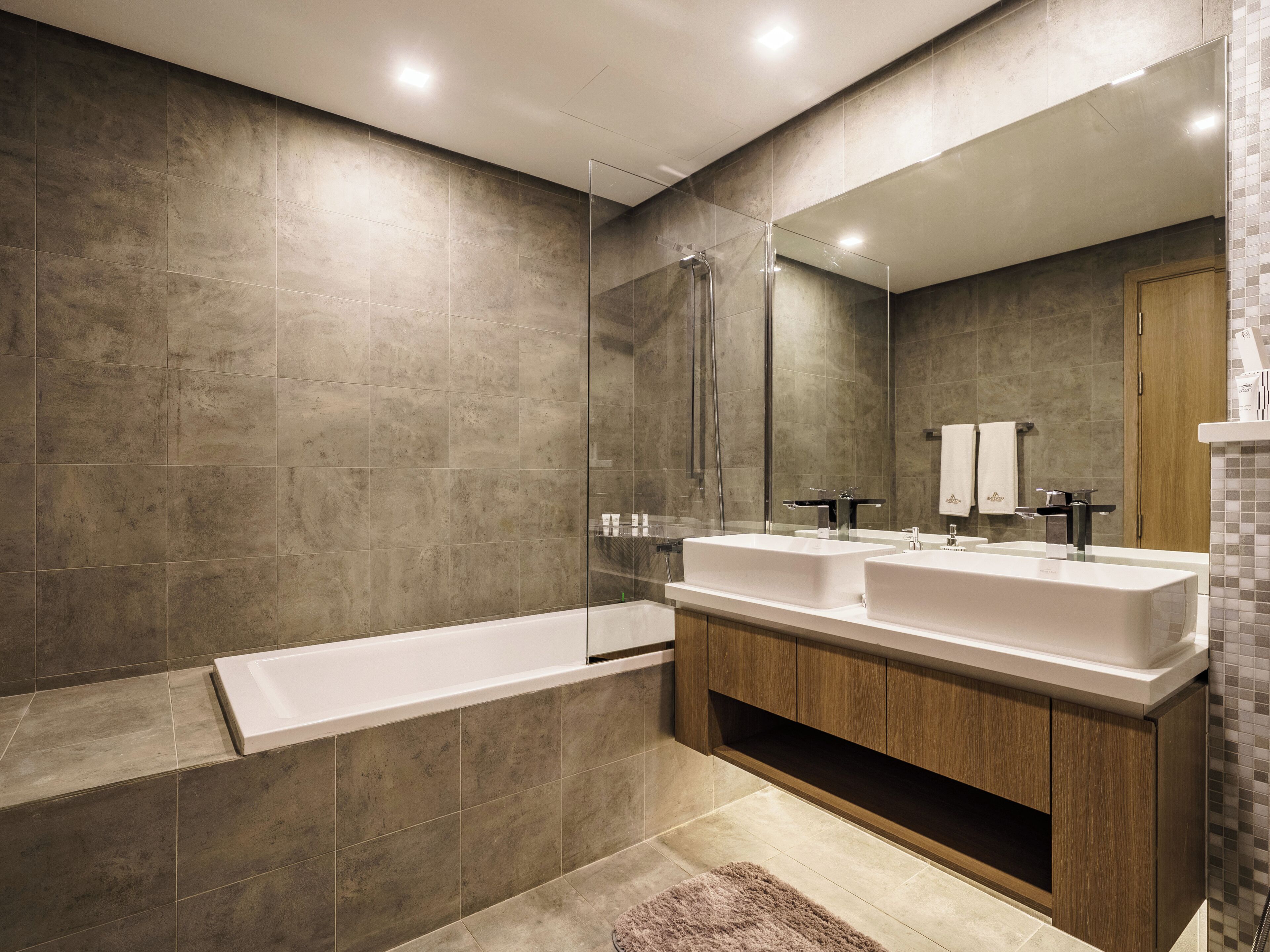 Une salle de bain moderne dotée d’une grande baignoire, d’une douche à l’italienne et d’un meuble-lavabo double.