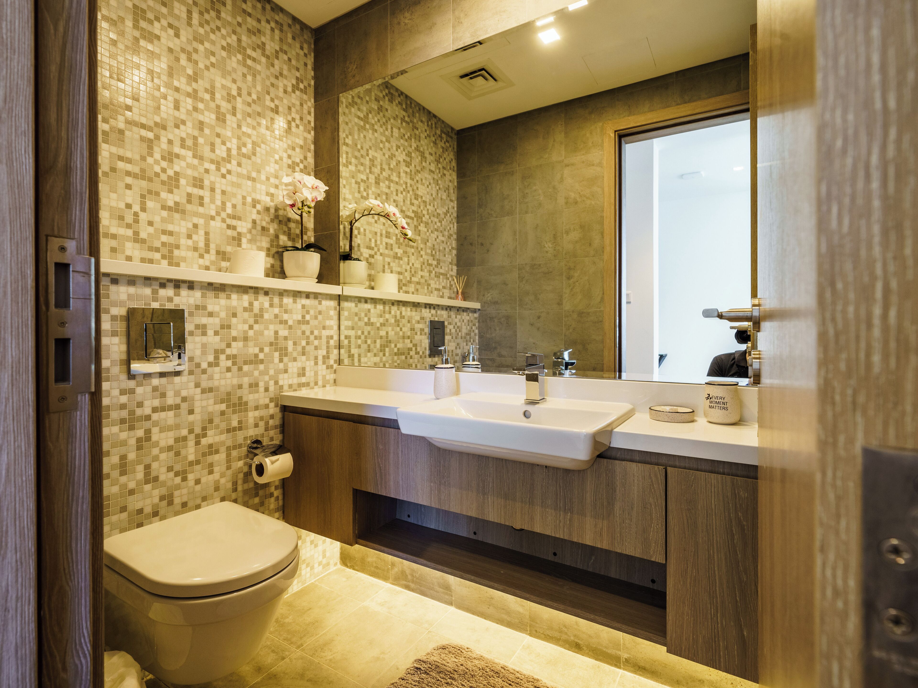 A modern bathroom with a toilet, sink, and mirror.