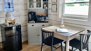Una cucina compatta con erogatore d'acqua, macchina da caffè, forno a microonde e pensili.