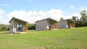 Three small, single-story buildings with a flat roof, a front door, and a small porch area. - Tiny House 4 - Farm Sanctuary, Finger Lakes (Watkins Glen)