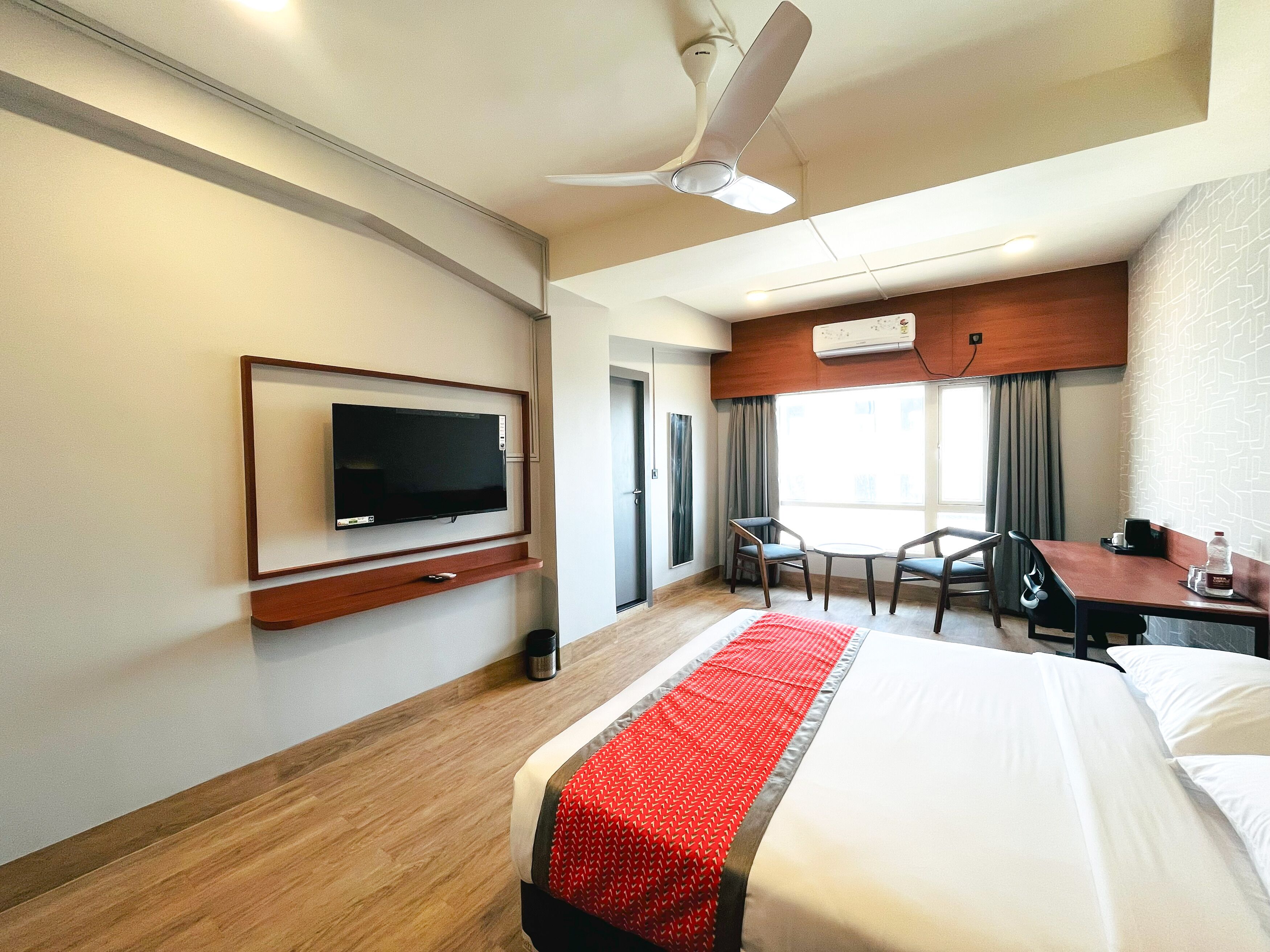 A hotel room with a bed, a TV, a desk, and a chair.