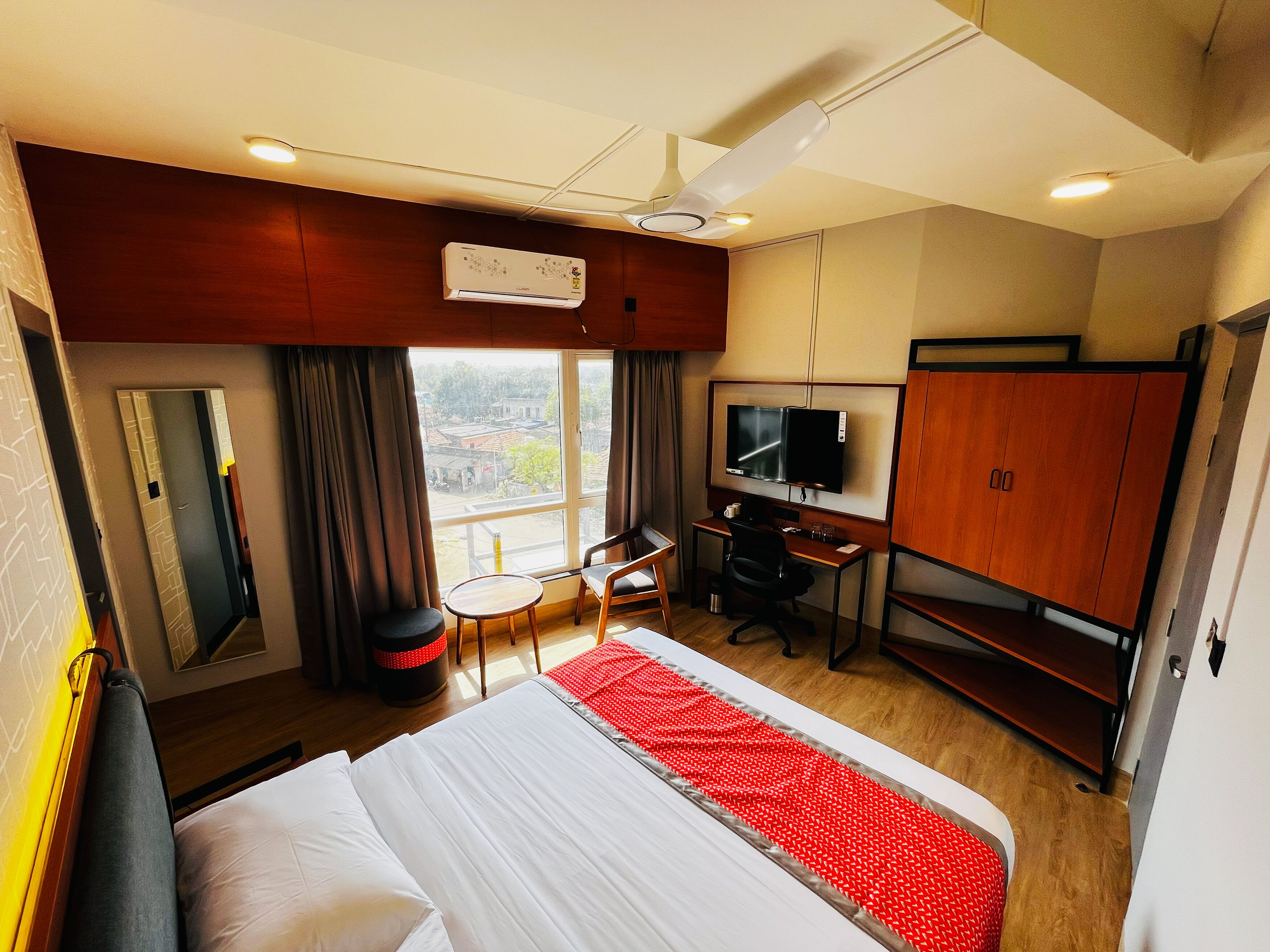 Una camera d'albergo con un letto, una scrivania, una televisione, un armadio e una finestra con vista.
