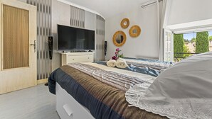 A bedroom with a bed, a TV, a window, and a door. - Holiday Home “Chez Dominique” with Private Pool, Wi-Fi, and Air Conditioning (Saint-Rémy-de-Provence)