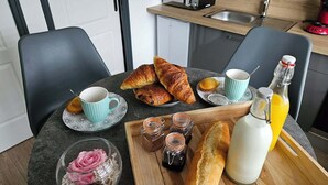 A breakfast setup with croissants, a cup, a bottle of orange juice, and jars of jam on a table. - L'Oxybulles and spa (Friville-Escarbotin)