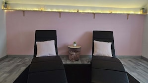 A room with two black chairs with white cushions, a small round table with a plant, and a wall-mounted light strip. - L'Oxybulles and spa (Friville-Escarbotin)