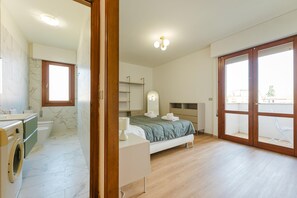 A bedroom with a bed, a bathroom with a toilet and washing machine, and a balcony with a view. - Lily Flat - 15 min from Venice (Mestre)