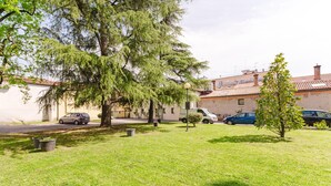 Un quartier résidentiel avec une pelouse, un arbre et des voitures garées.