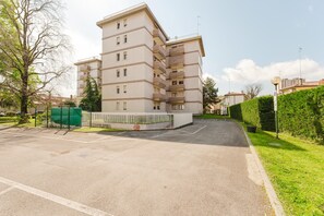 A multi-story residential building with balconies, a parking lot, and a hedge along the sidewalk. - Lily Flat - 15 min from Venice (Mestre)