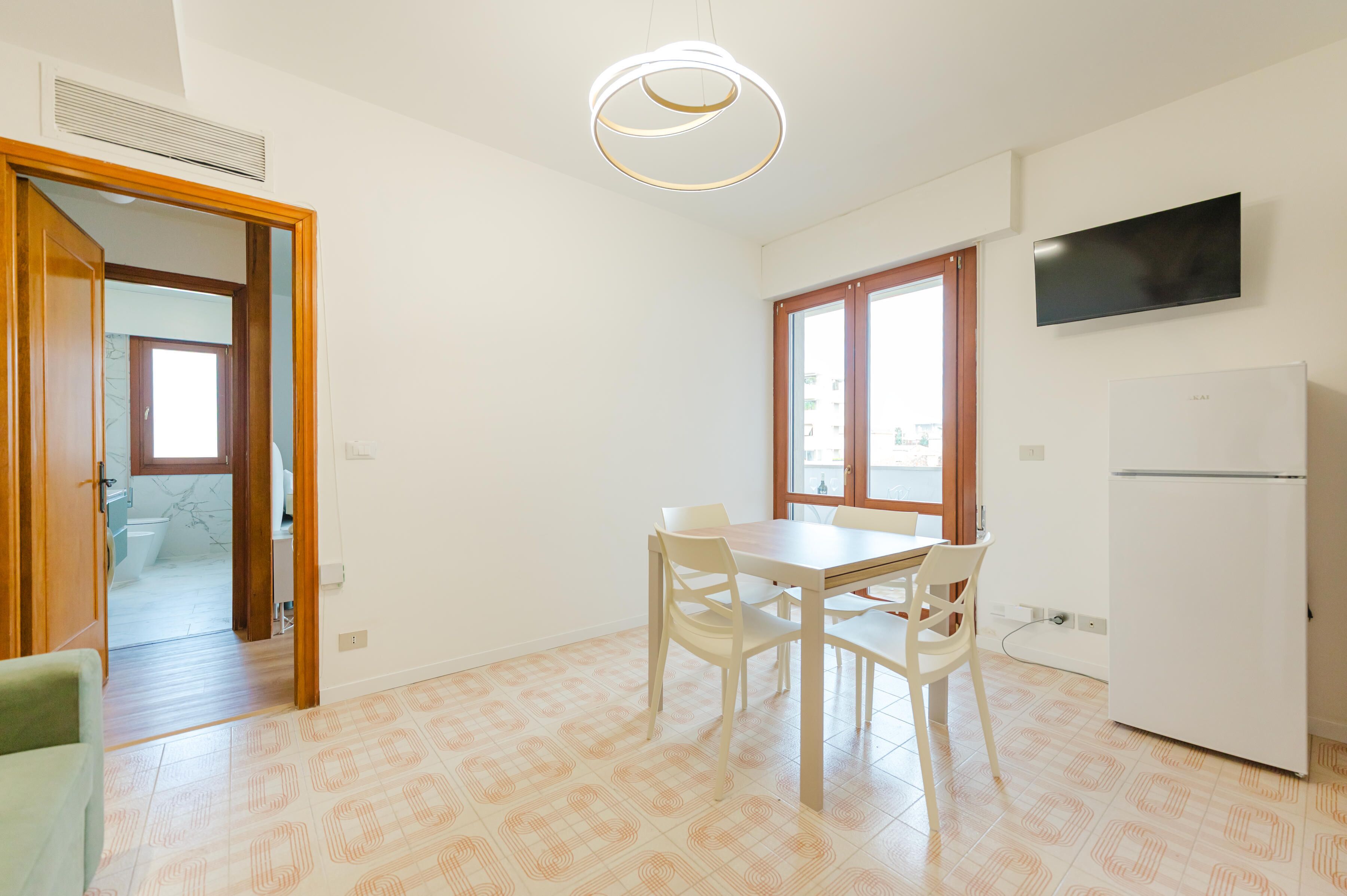 A kitchen with a dining table, chairs, a TV, and a refrigerator.