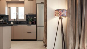 A modern kitchen with a central island, a refrigerator, and a window. - Etherio Naxos Ouranos Charming 2-bedroom apartment with AC in beautiful Naxos (Cyclades)