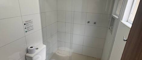 Un baño pequeño y limpio con inodoro, lavamanos y ducha.