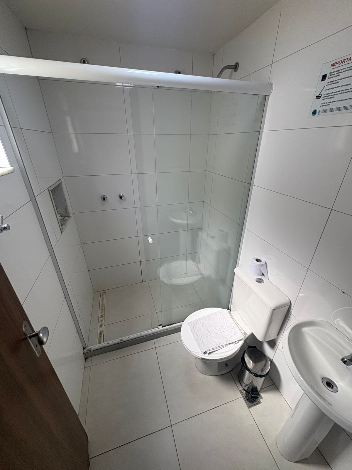 A bathroom with a glass-enclosed shower, a toilet, and a sink.