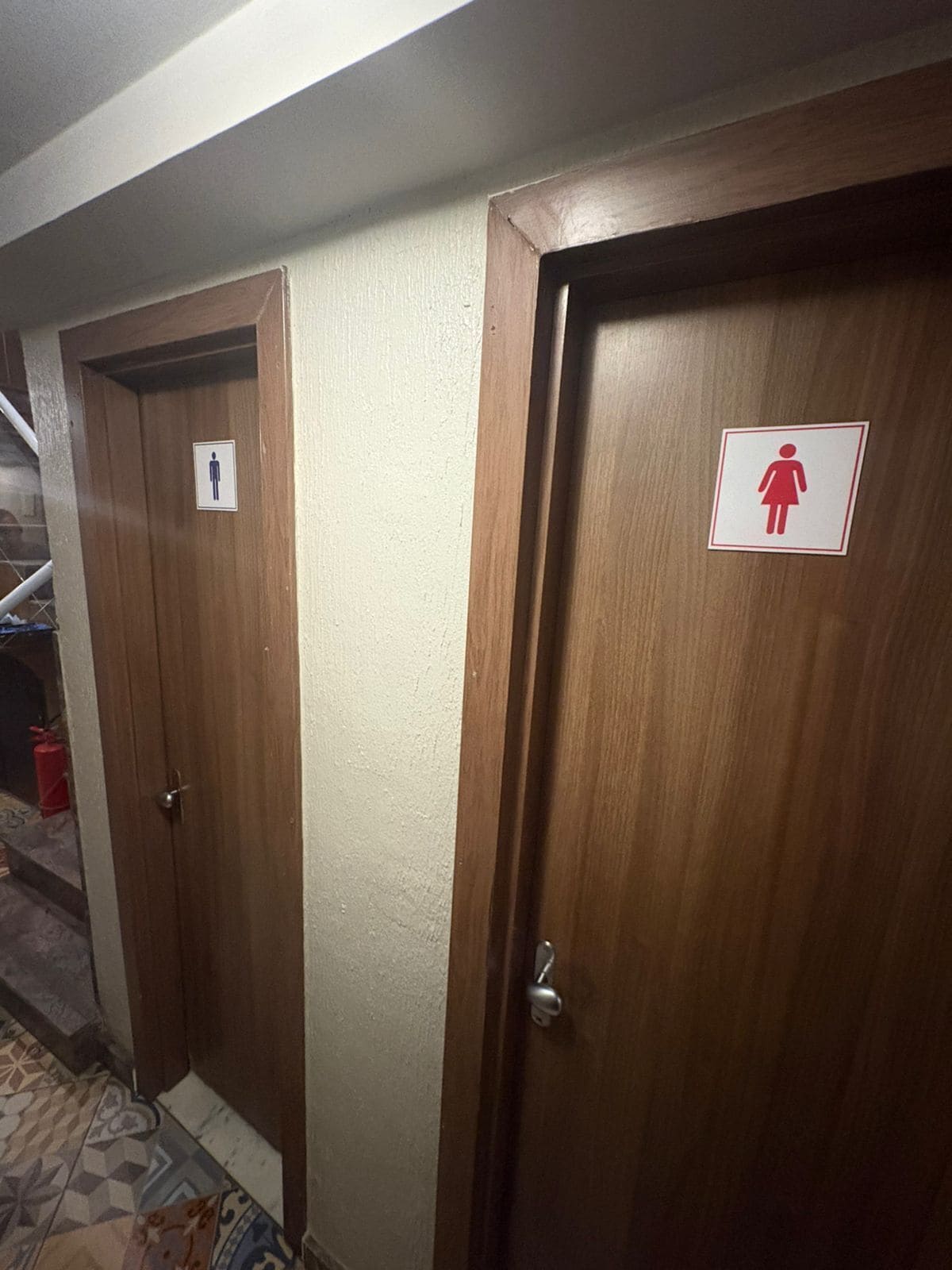 A hallway with two wooden doors, one marked for men and the other for women, leading to private rooms.