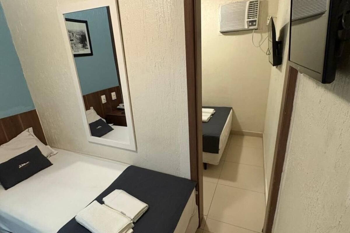 Ein Hotelzimmer mit einem Bett, einem Spiegel, einem Fernseher und einem kleinen Tisch.
